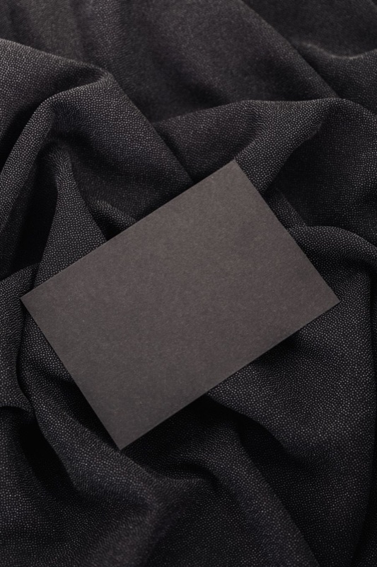 A black card on dark fabric — the Legacy Card, its face reserved for the house mark